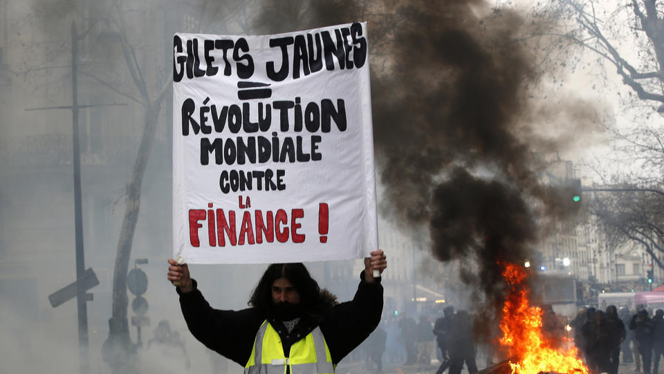 26.01.2019, Frankreich, Paris: Ein Demonstrant hält ein Schild mit der Aufschrift «Gelbwesten = weltweite Revolution gegen die Finanzwirtschaft». In der französischen Hauptstadt kam es zu erneuten «Gelbwesten»-Protesten. Die Aktionen richten sich gegen di 26.01.2019, Frankreich, Paris: Ein Demonstrant hält ein Schild mit der Aufschrift «Gelbwesten = weltweite Revolution gegen die Finanzwirtschaft». In der französischen Hauptstadt kam es zu erneuten «Gelbwesten»-Protesten. Die Aktionen richten sich gegen di