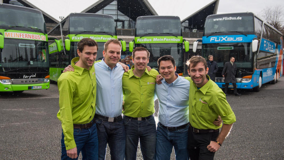 Die Geschäftsführer des Unternehmens "FlixBus MeinFernbus" Jochen Engert (l-r), Torben Greve, Andre Schwämmlein, Panya Putsathit und Daniel Krauss stehen am 09.01.2015 in Berlin vor Reisebussen (Personengruppe von hinten angeblitzt). Am 07.01.2015 wurde b