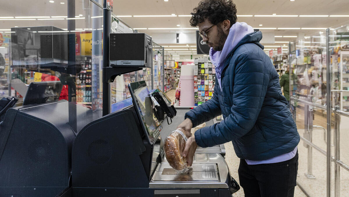 Side view of a man shopping in a supermarket while on a budget. He is scanning his items at the self service checkout in the North East of England. Side view of a man shopping in a supermarket while on a budget. He is scanning his items at the self service checkout in the North East of England.
